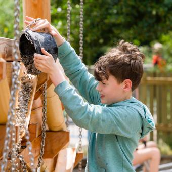 Boy tipping gravel from a bucket into a shoot